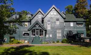 Front view of the green Weyerhaeuser mansion at the Linden Hill Historic Estate in Little Falls, Minnesota. Perfect historic event space for group lodging for weddings, reunions, retreats, and other events.